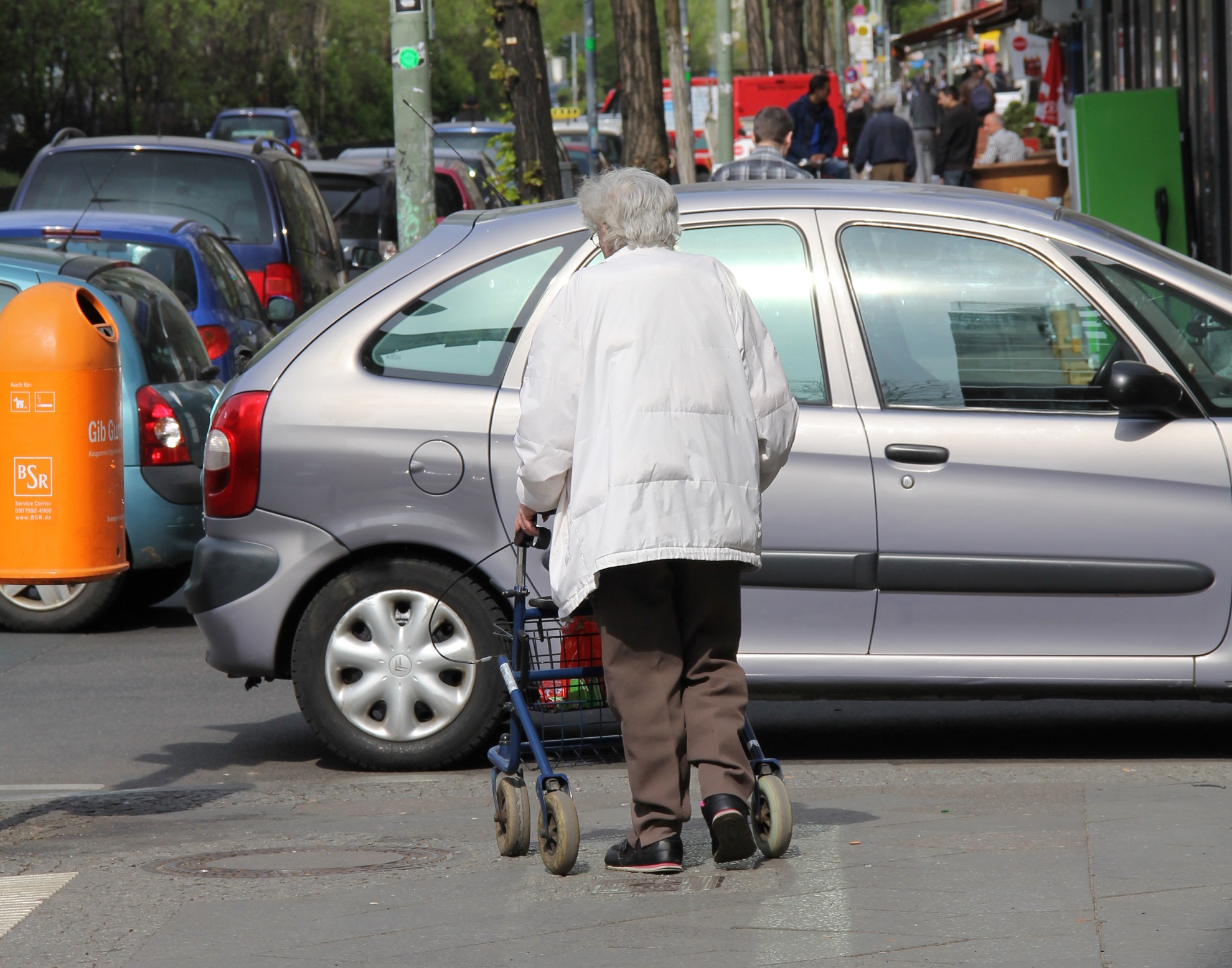 Foto: Ein Auto parkt verkehrswidrig zu nah an der Kreuzung und versperrt damit einer älteren Frau mit Rollator den Übergang zur anderen Straßenseite. Foto: ABSV/Rändel